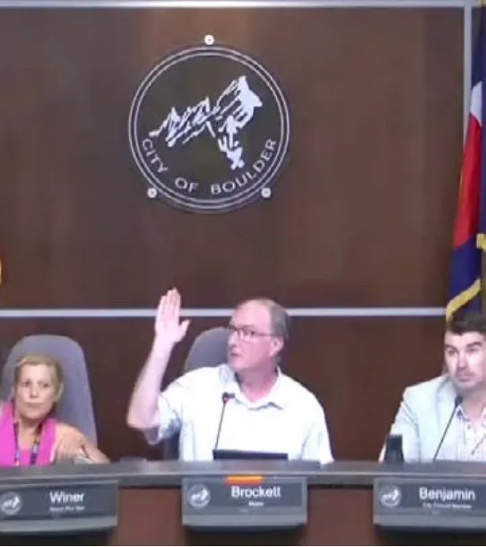 Boulder City Council members Tara Winer, Aaron Brockett and Matt Benjamin at the dais; Brockett has his hand raised.