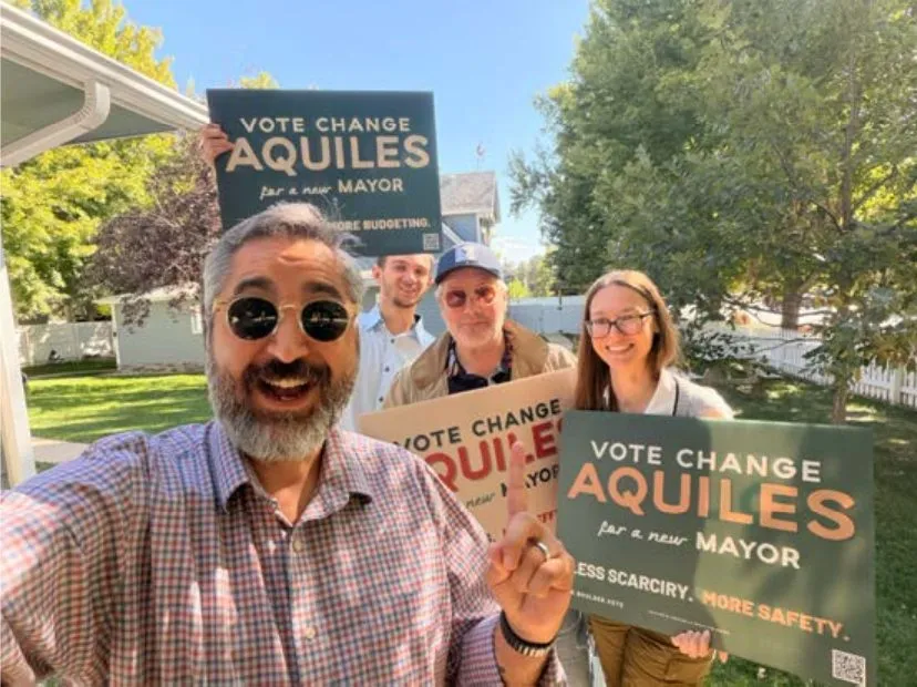 Aquiles La Grave takes a selfie with three supporters holding “Vote Change Aquiles for a new Mayor” yard signs.